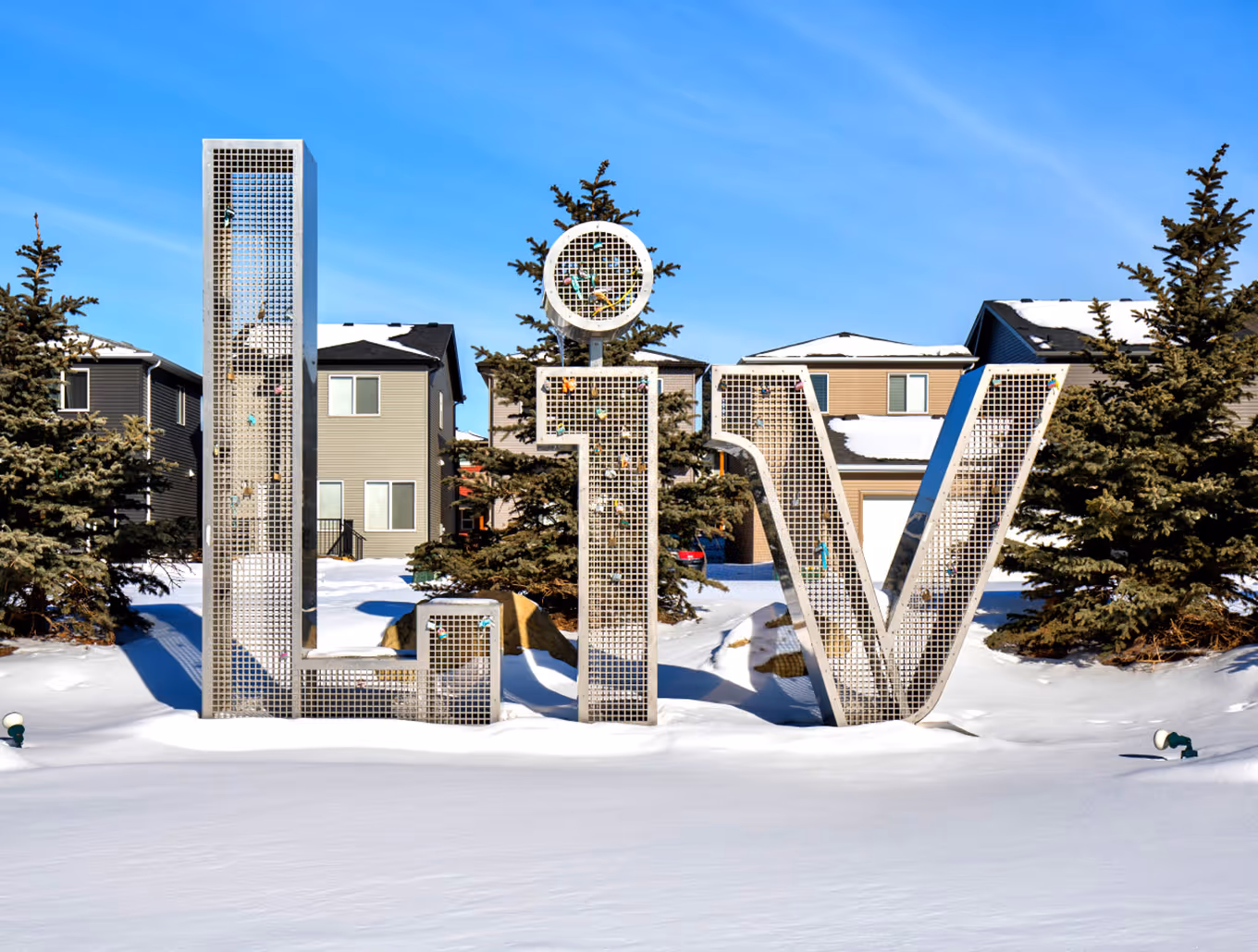 Stainless steel “LIV” monument with ribbon-cutting detail, highlighting the sculptural letterforms and durable outdoor construction.
