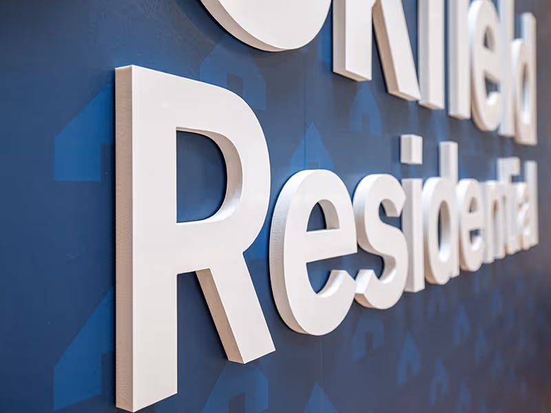 Interior consultation space featuring a central island, material displays, and Brookfield Residential branded feature wall.