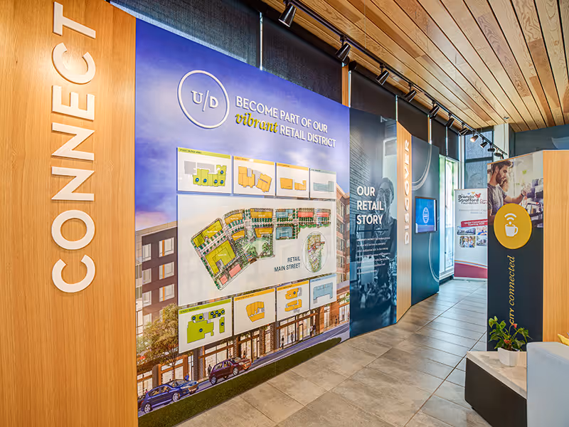 Interior corridor of the Discovery Centre showcasing modular wall displays, layered graphics, and retail district maps.