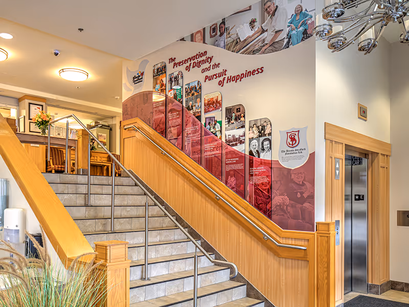 Wide view of The Brenda Strafford Foundation stairwell installation with curved graphic overlays, dimensional text, and integrated photography.