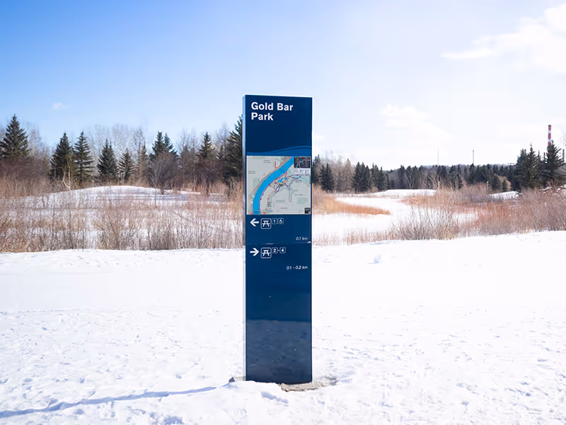 Tall Gold Bar Park map and directional sign standing in an open, snow-covered park setting.