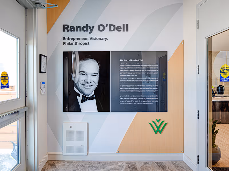 Interior donor recognition wall at Randy O’Dell House, featuring dimensional lettering, portrait panels, and layered materials in a bright entryway.