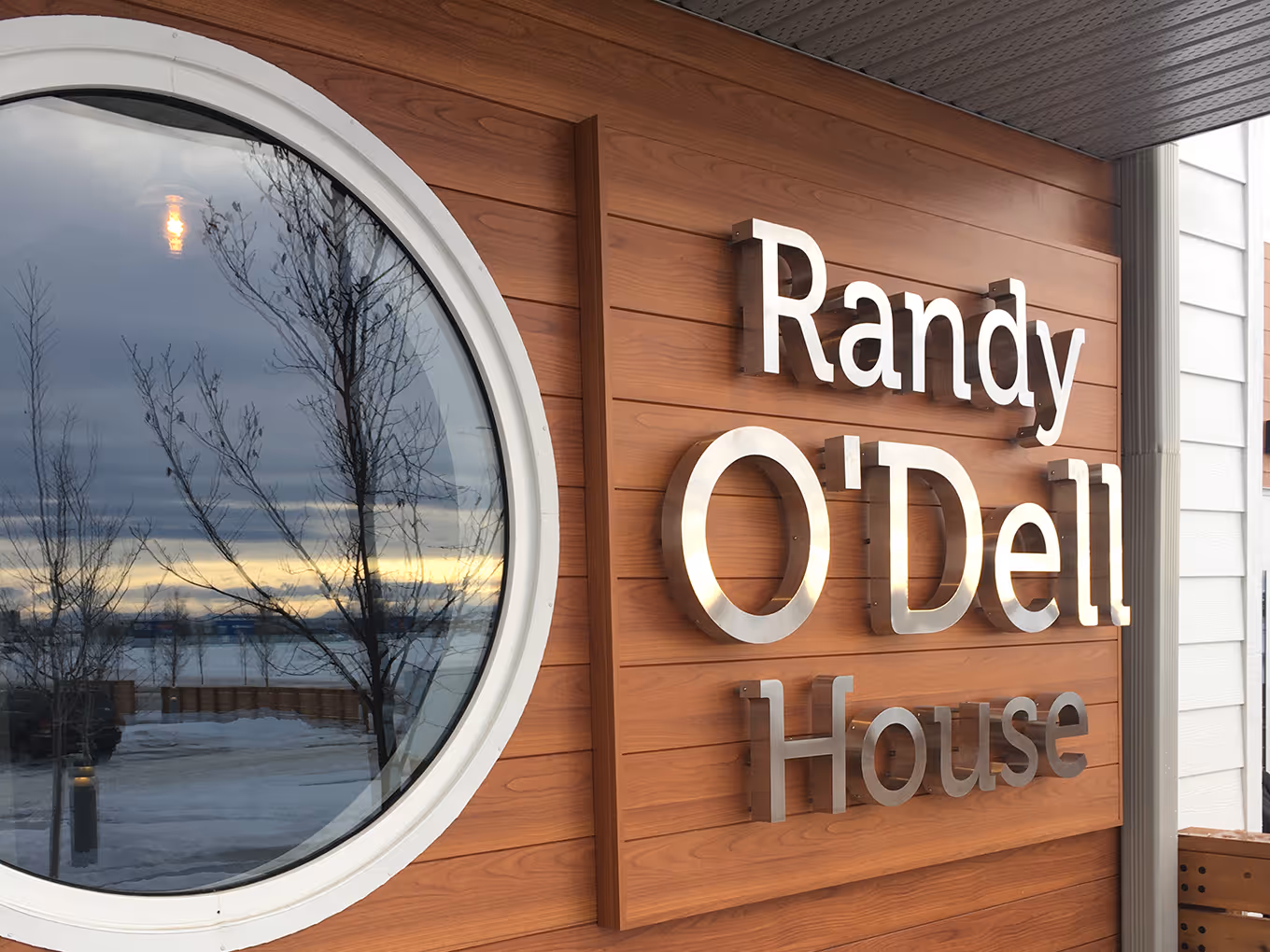 Halo-lit dimensional lettering spelling “Randy O’Dell House” mounted on a wood-clad exterior wall.