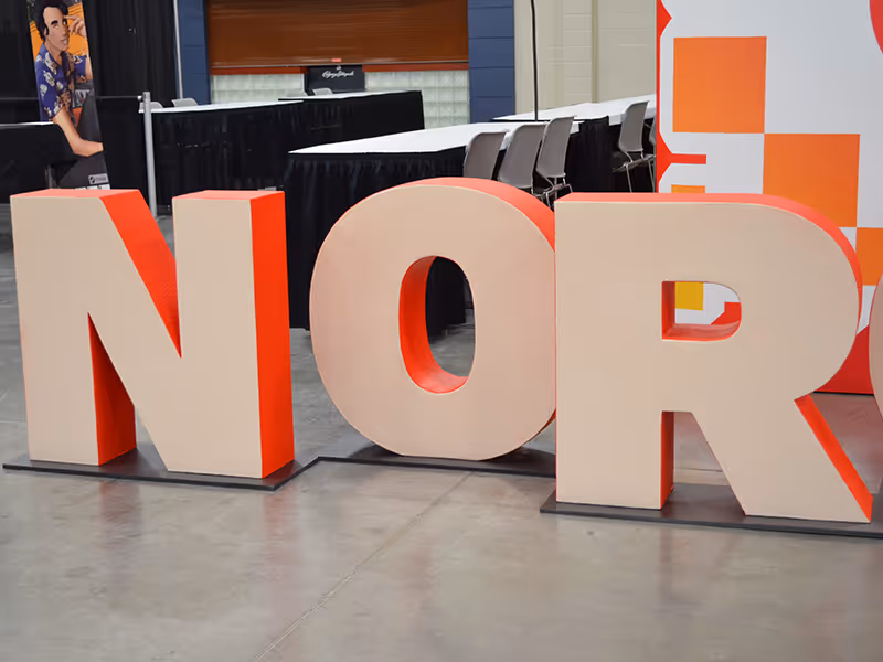 Close-up of oversized hard-coated foam letters spelling “NOR” as part of a NorQuest College display.
