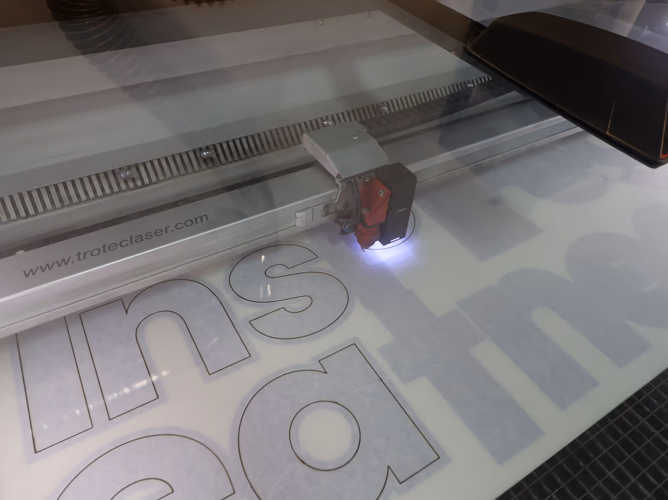 Trotec laser cutter engraving large custom letters for trade show signage in Exhibit Studio’s fabrication shop.