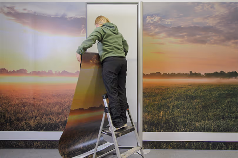 Exhibit team member replacing trade show display graphics on modular booth to refresh branding without full rebuild.