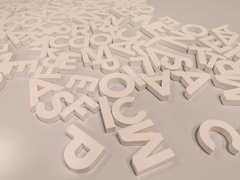 White dimensional cut letters spread across a work surface during fabrication of custom signage for the Taza Park marketing centre project.