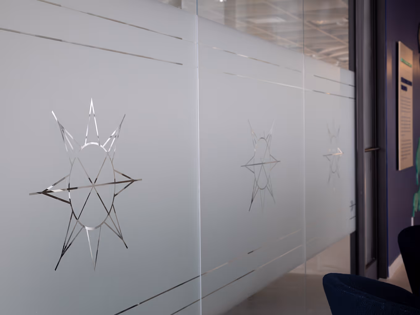 Close-up of frosted glass privacy film featuring an etched Taza Park eight-pointed star motif with geometric line detailing.
