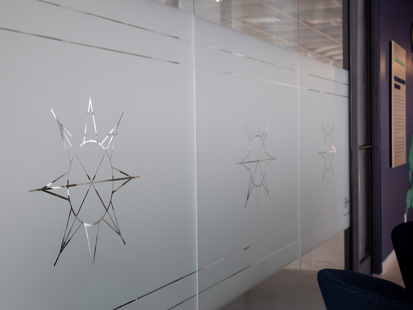 Close-up of frosted glass privacy film featuring an etched Taza Park eight-pointed star motif with geometric line detailing.