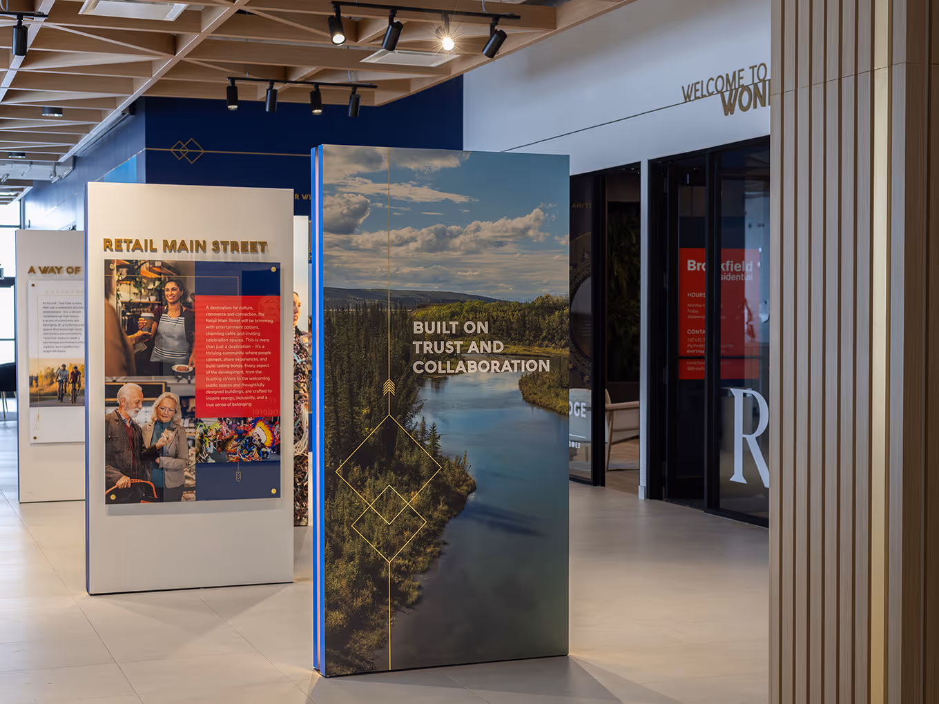 Interior of Taza Park marketing centre with interpretive panels for Retail Main Street and a landscape panel reading "Built on Trust and Collaboration."
