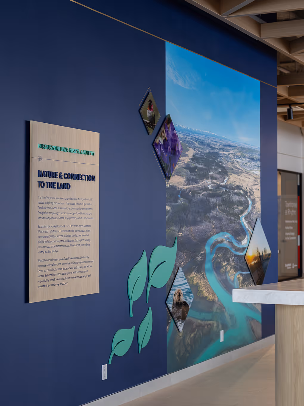 "Nature & Connection to the Land" interpretive wall display at Taza Park marketing centre with aerial landscape photography and wildlife imagery.