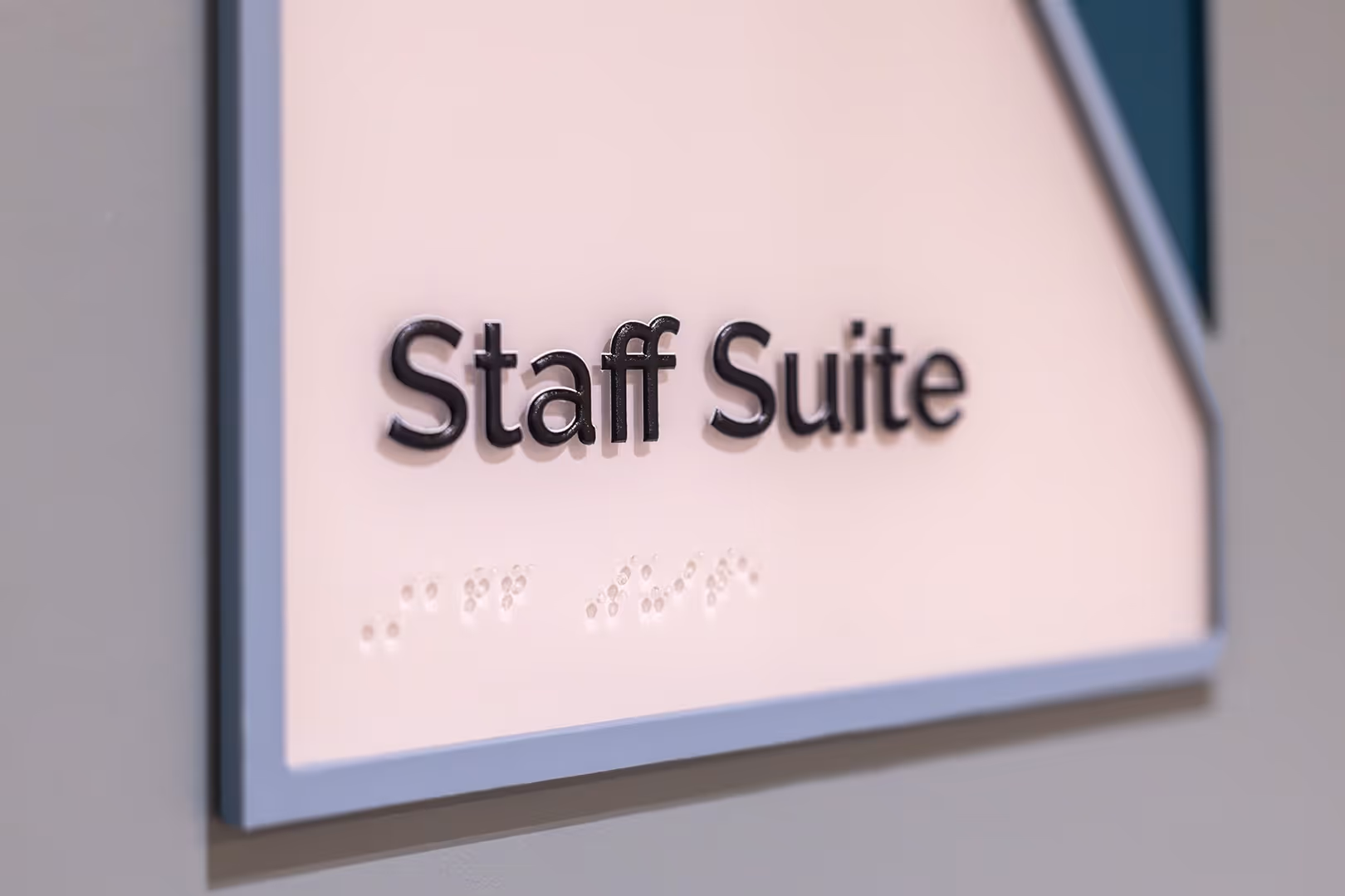 Close-up of “Staff Suite” room sign with raised lettering and braille for accessibility.