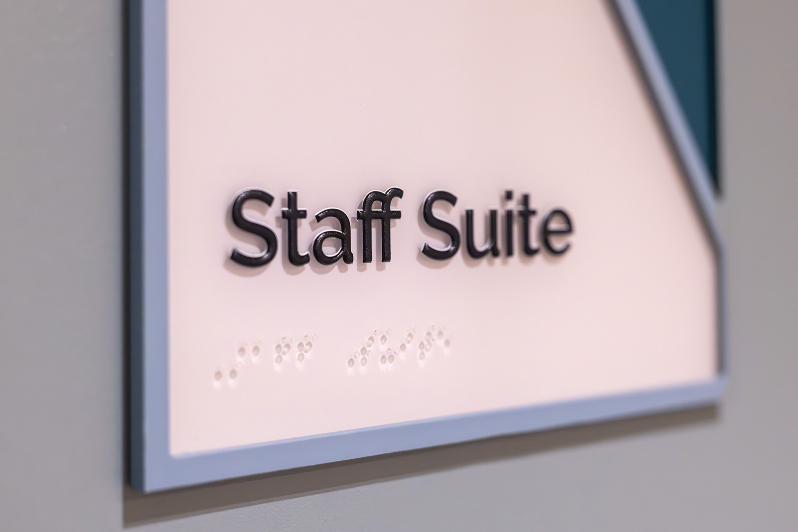 Close-up of “Staff Suite” room sign with raised lettering and braille for accessibility.