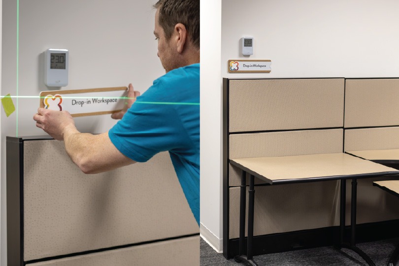 two images, left showing a vertical wayfinding sign displaying an open work space and the right image showing the signage being installed.