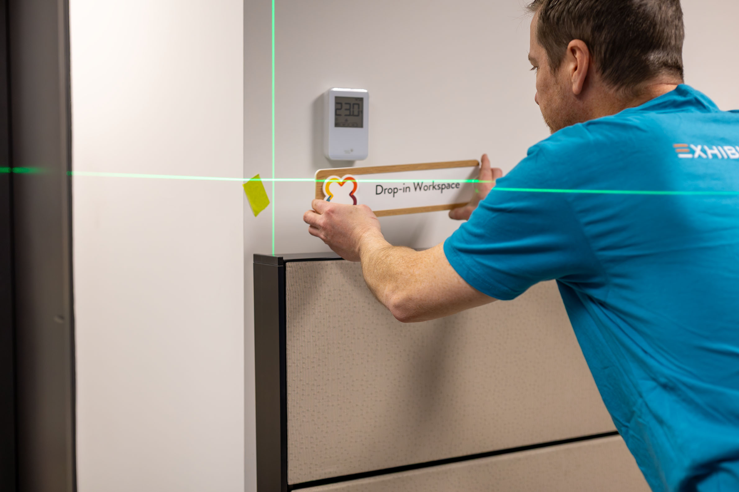 Wayfinding signage being installed by an Exhibit Studio team member.