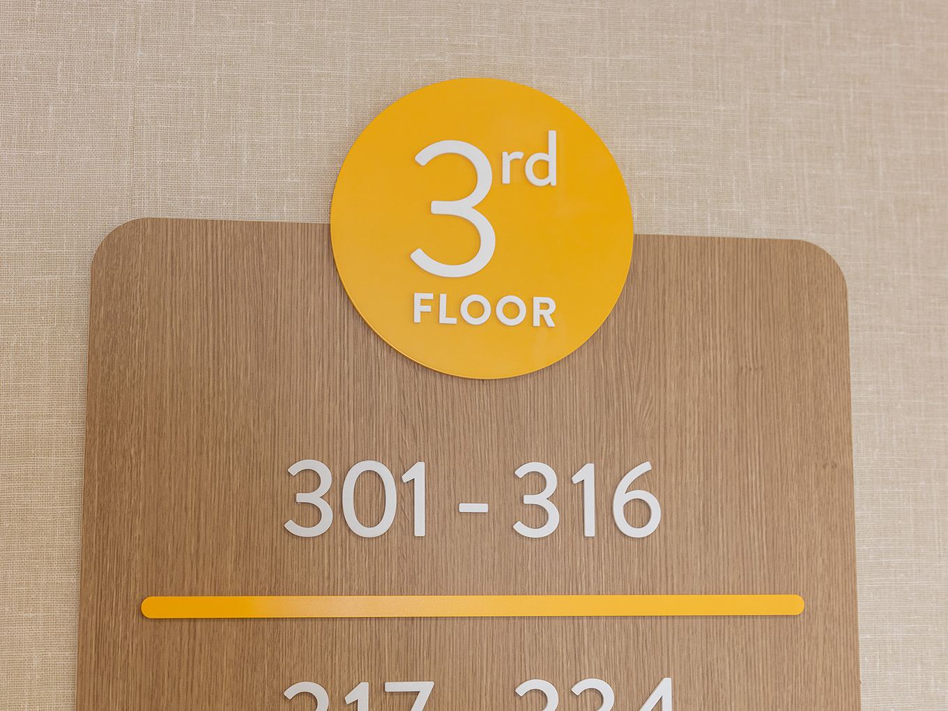 Floor identifier sign for the third floor at United Active Living Garrison Green, featuring a yellow circular badge, dimensional numerals, and room range 301–316.