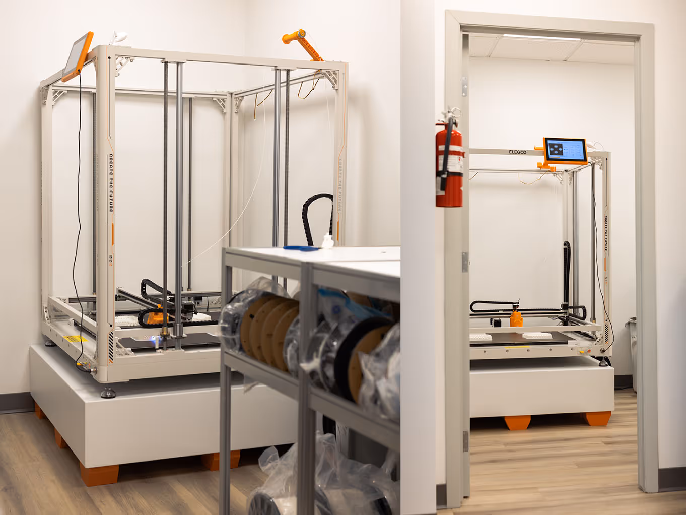 Elegoo OrangeStorm Giga large-format 3D printer on custom-built base at Exhibit Studio's fabrication facility, shown beside a doorframe for scale