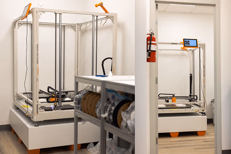 Elegoo OrangeStorm Giga large-format 3D printer installed in Exhibit Studio's dedicated fabrication room, with doorframe showing full machine scale