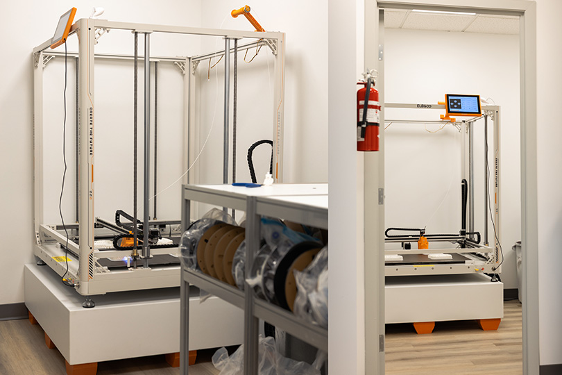 Elegoo OrangeStorm Giga large-format 3D printer installed in Exhibit Studio's dedicated fabrication room, with doorframe showing full machine scale