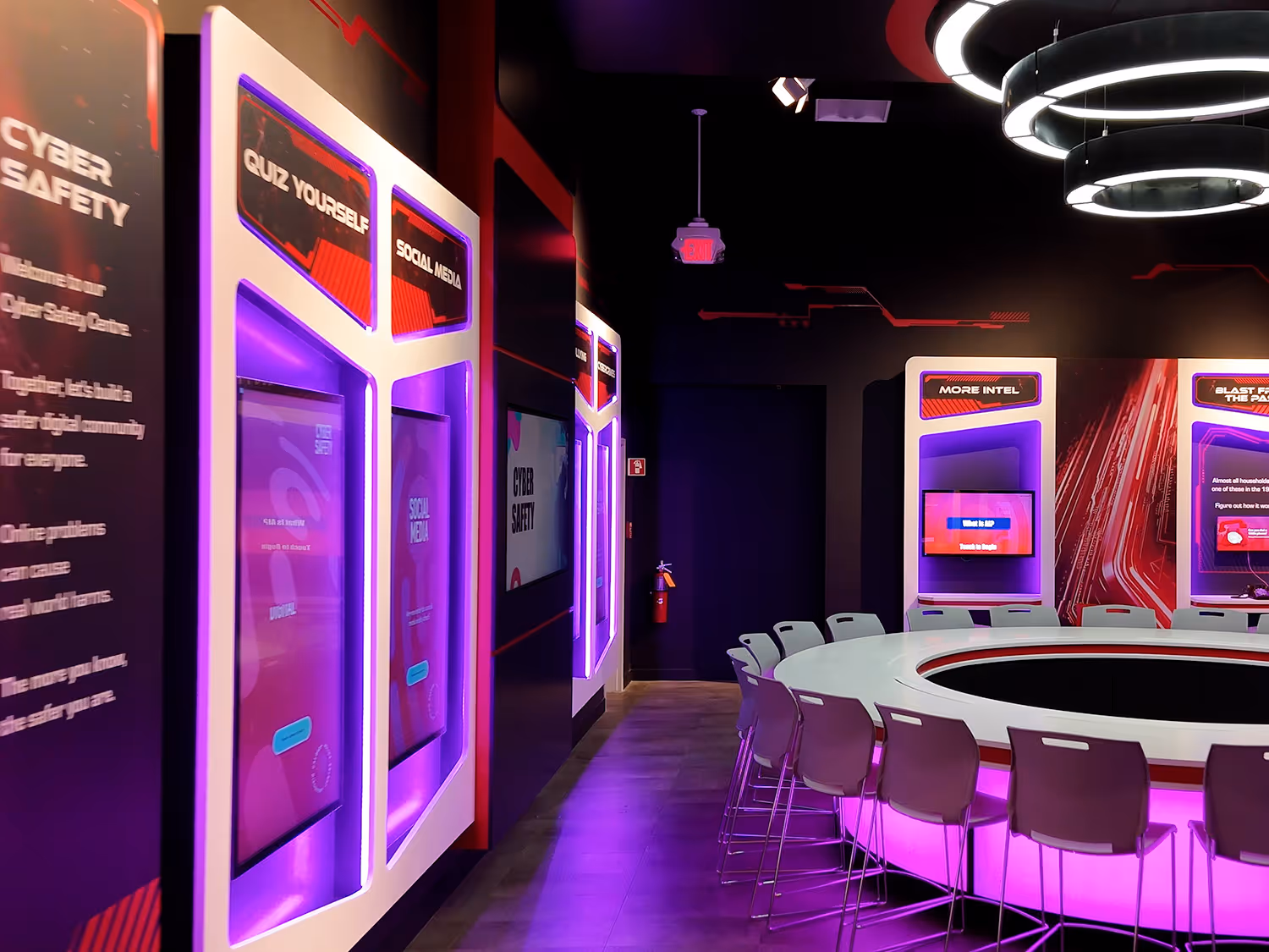 Cyber Safety Centre showing backlit Quiz Yourself and Social Media kiosks on the left, with the welcome panel and More Intel station visible in the background.