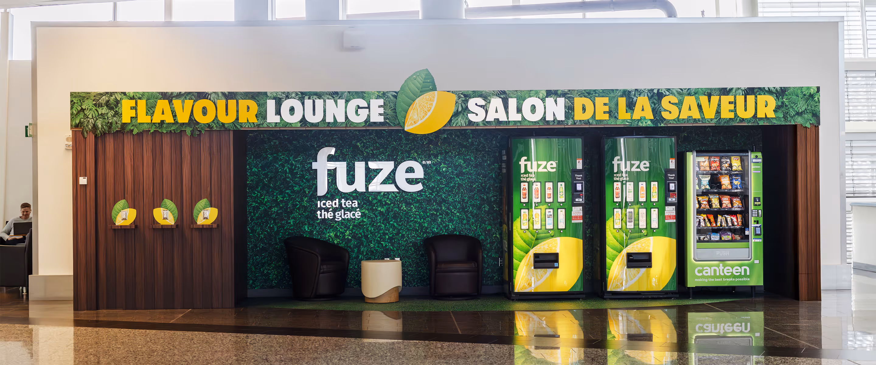 Fuze Iced Tea Flavour Lounge brand activation at Calgary International Airport featuring green wall, vending machines, and seating area