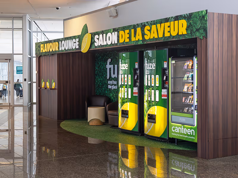 Fuze Iced Tea branded vending machine kiosk with Canteen snack machine inside Calgary Airport Flavour Lounge activation