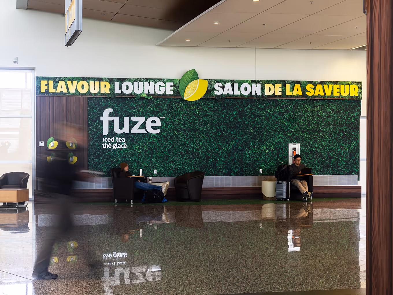 Fuze Iced Tea Flavour Lounge green wall with dimensional logo signage and lounge seating at Calgary Airport