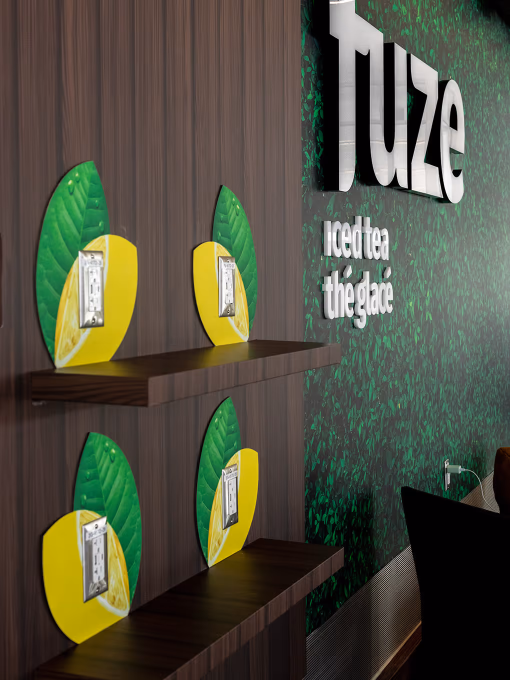Custom lemon-shaped USB and power charging stations mounted on wood-panel wall inside Fuze Flavour Lounge activation