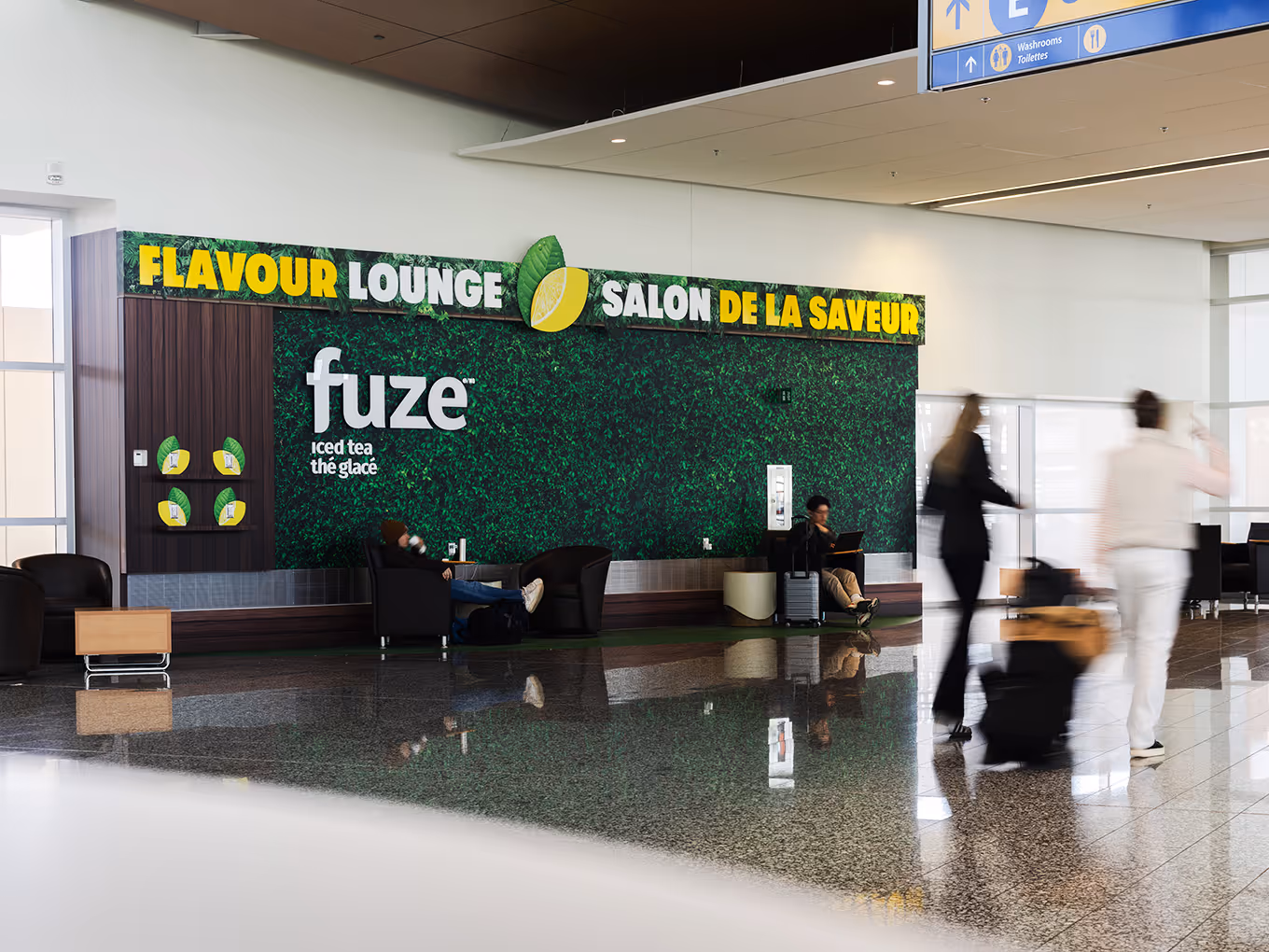 Fuze Iced Tea Flavour Lounge full wall brand activation with travellers and luggage at Calgary International Airport