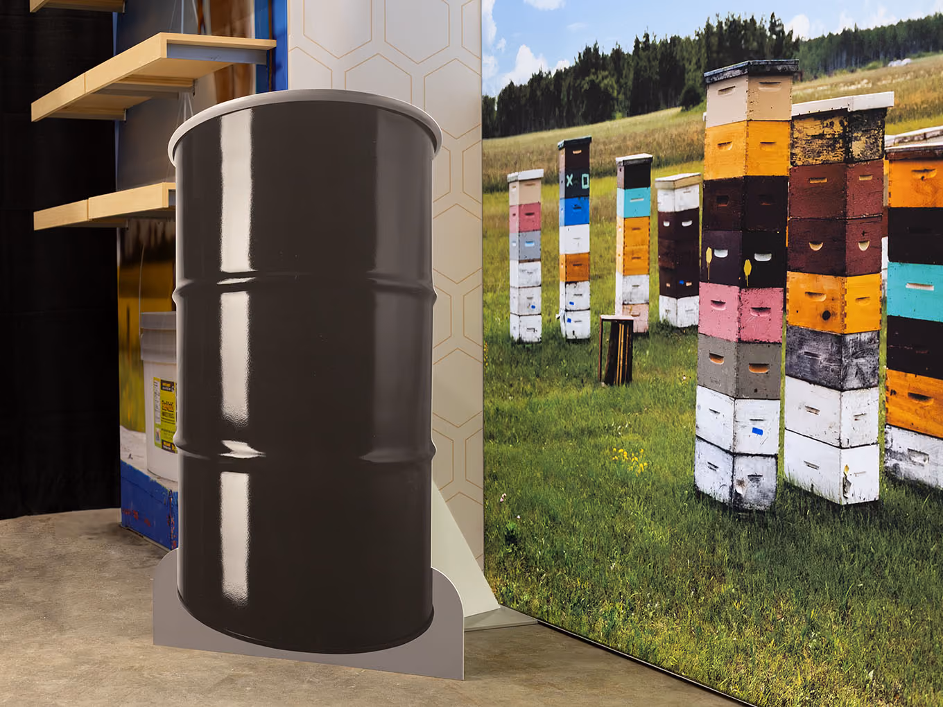 Large-scale honey barrel prop cutout beside BeeMaid Honey colorful beehive field photo mural — custom trade show display props and large-format graphics.