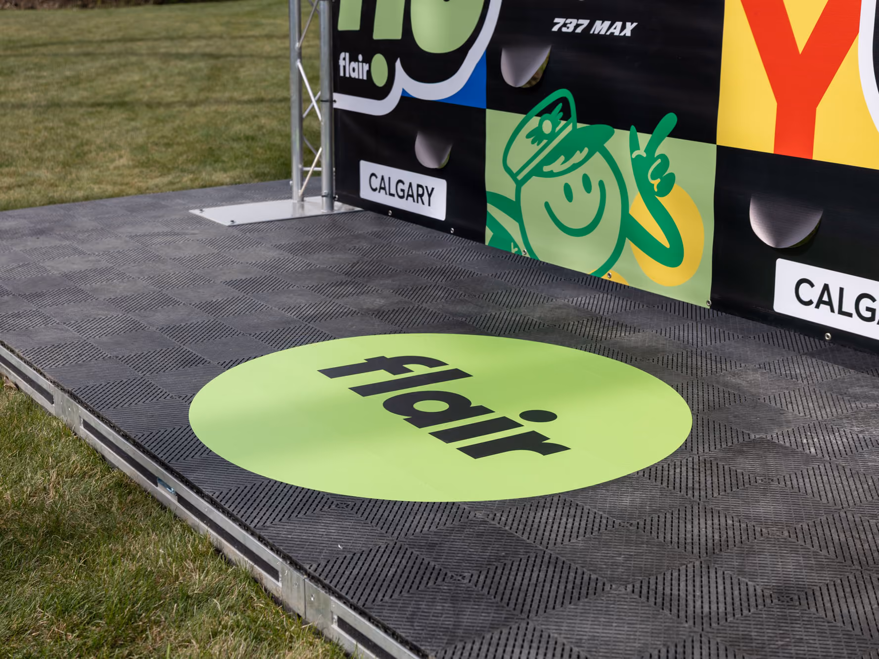 Close-up of the textured black non-slip stage with a green circular Flair decal at the base of the Calgary Marathon graphics.