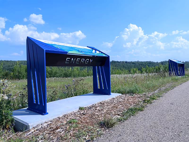 Front view of the "Spirit" interpretive panel installed beside a paved trail through open grassland.