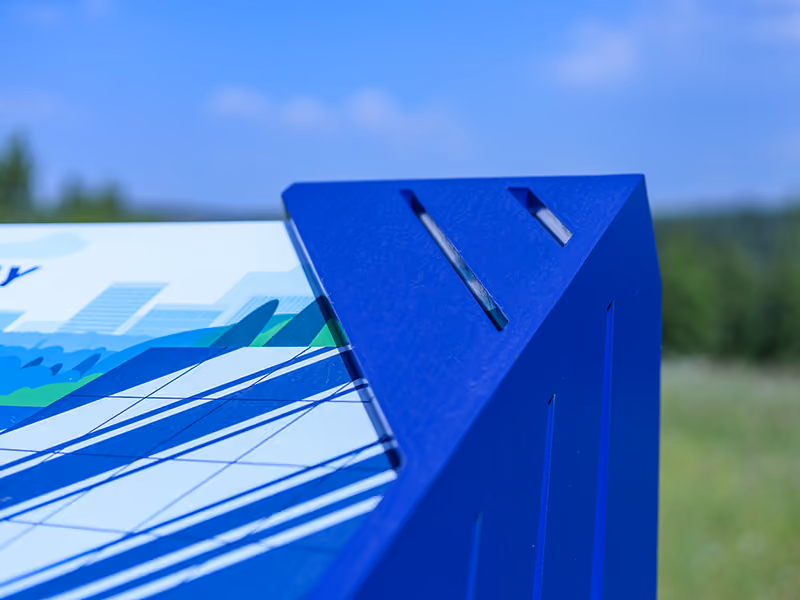 	Close-up of a powder-coated blue steel corner joint on an outdoor interpretive sign frame.