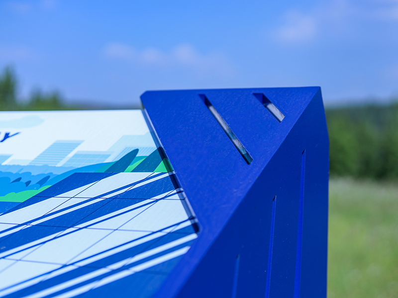 Close-up of a powder-coated blue steel corner joint on an outdoor interpretive sign frame.