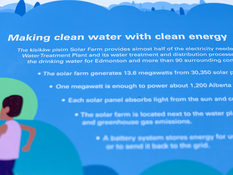 Close-up of interpretive graphic text reading "Making clean water with clean energy" on a solar farm sign.