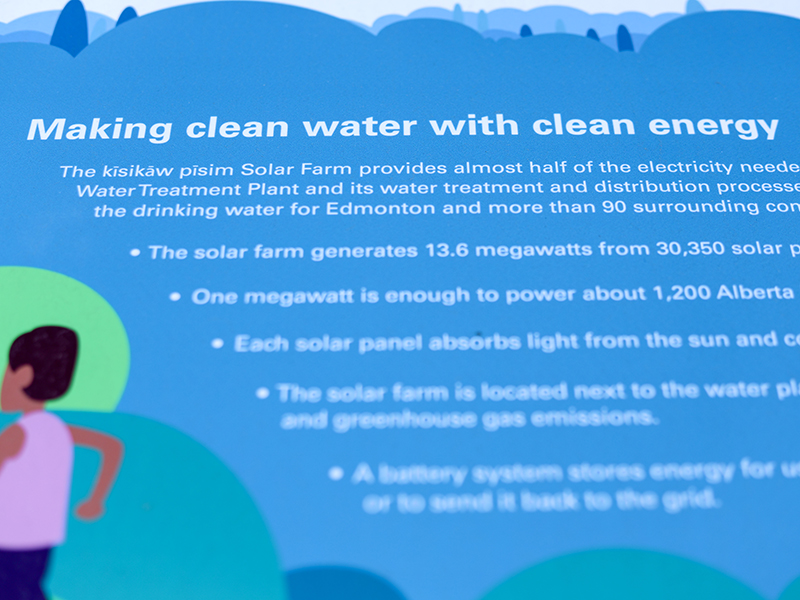 Close-up of interpretive graphic text reading "Making clean water with clean energy" on a solar farm sign.