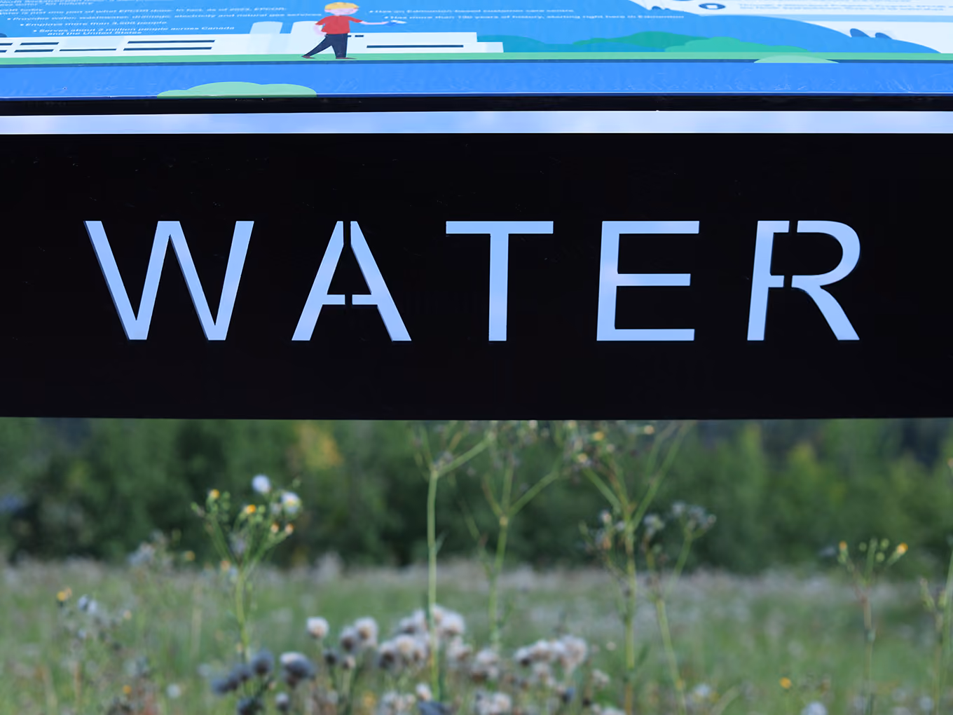 	Close-up of laser-cut "Water" lettering on a black powder-coated steel panel.