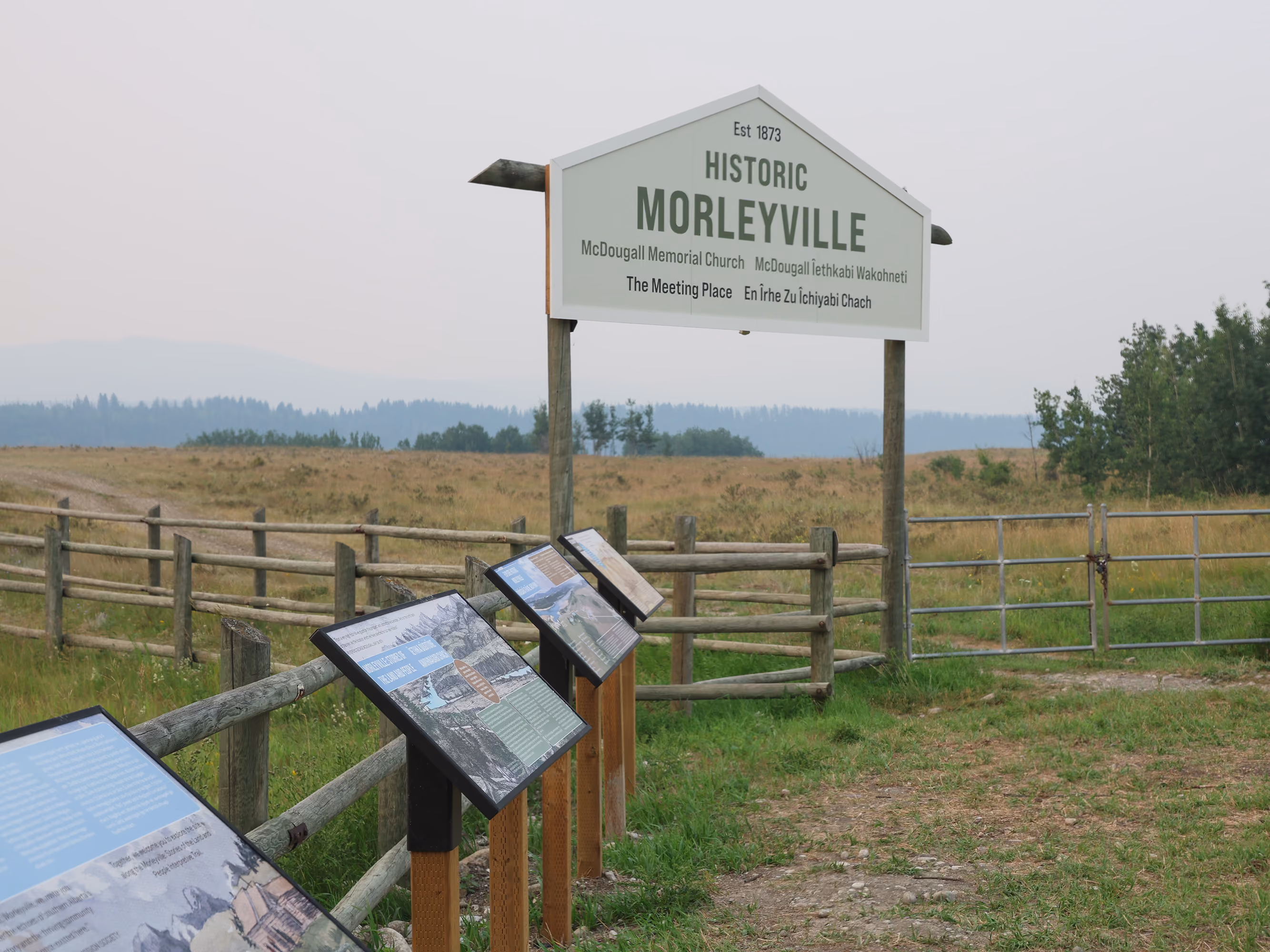 Historic Morleyville arch entrance sign viewed from the trail with a line of interpretive panels approaching it.