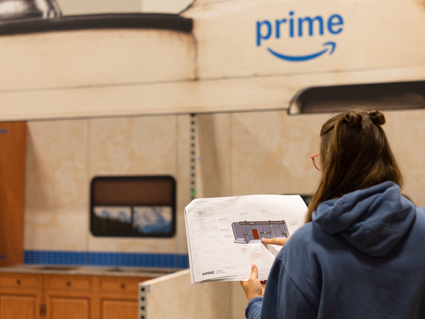 An Exhibit Studio team member reviews construction drawings in front of the custom RV façade during install.