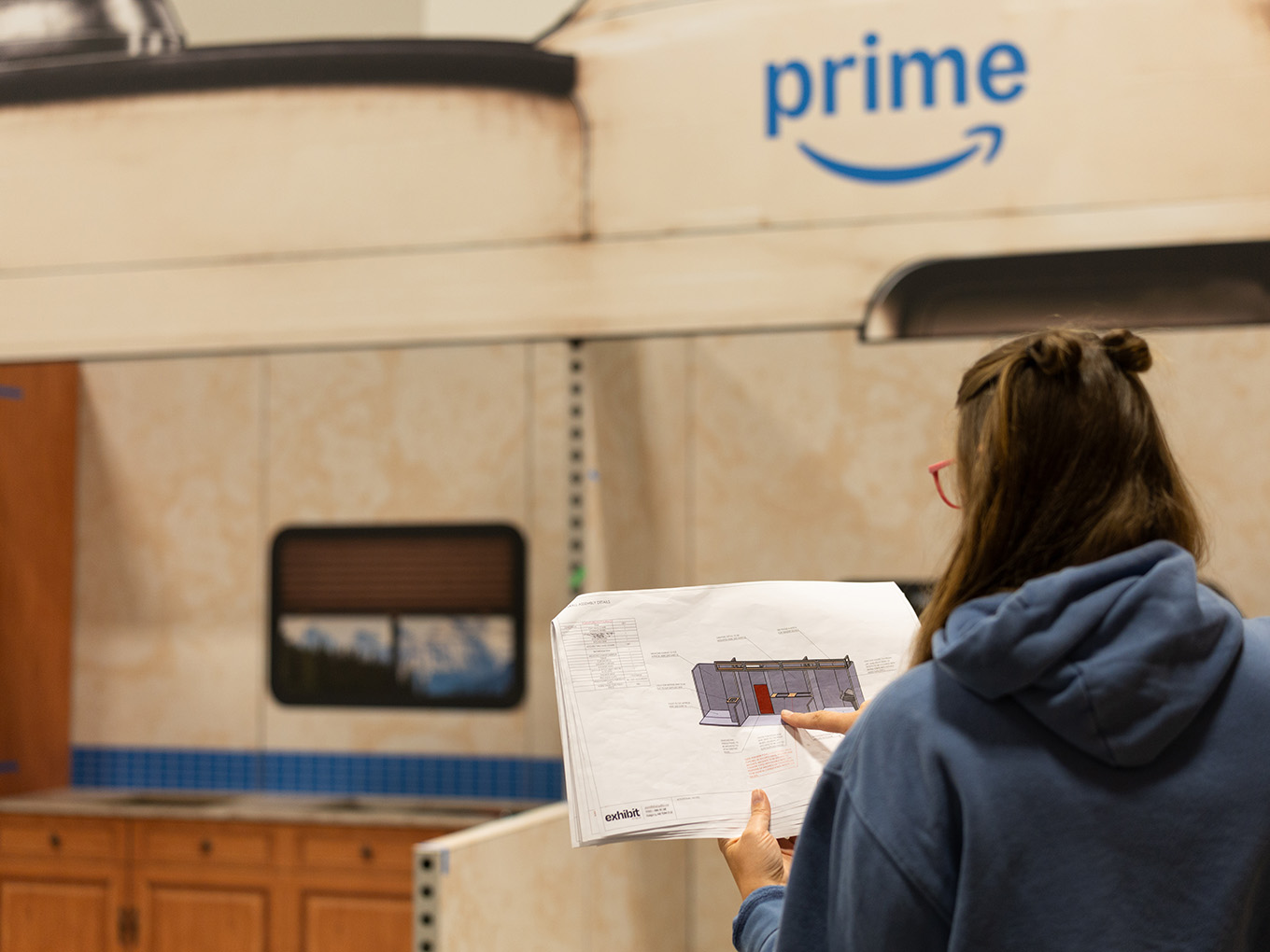 An Exhibit Studio team member reviews construction drawings in front of the custom RV façade during install.