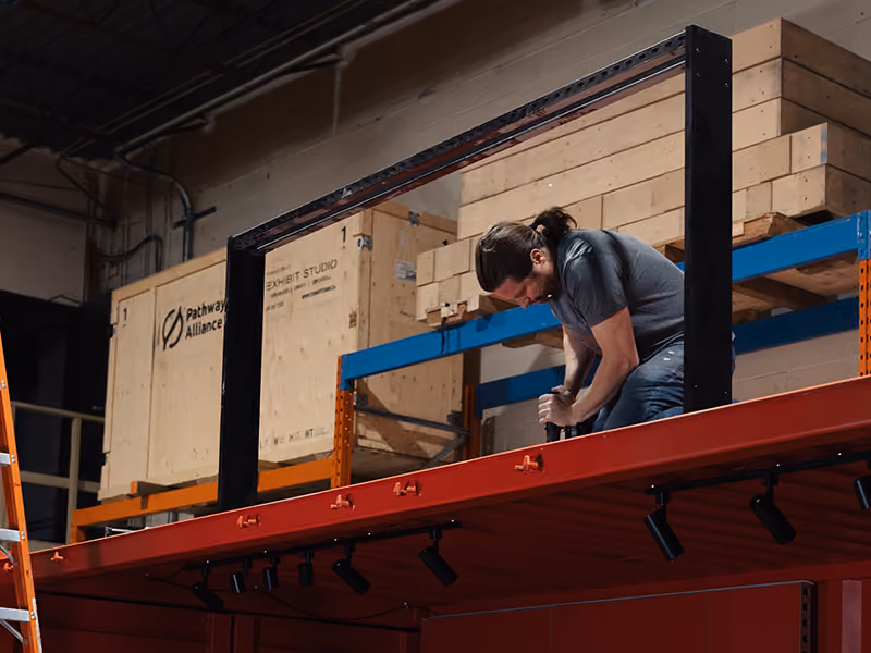 Exhibit Studio fabricator assembling a custom steel sign frame for the Coca-Cola Ink Studio seacan build.