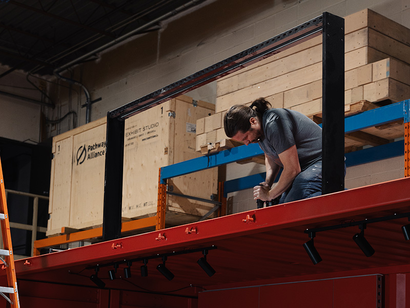 Exhibit Studio fabricator assembling a custom steel sign frame for the Coca-Cola Ink Studio seacan build.
