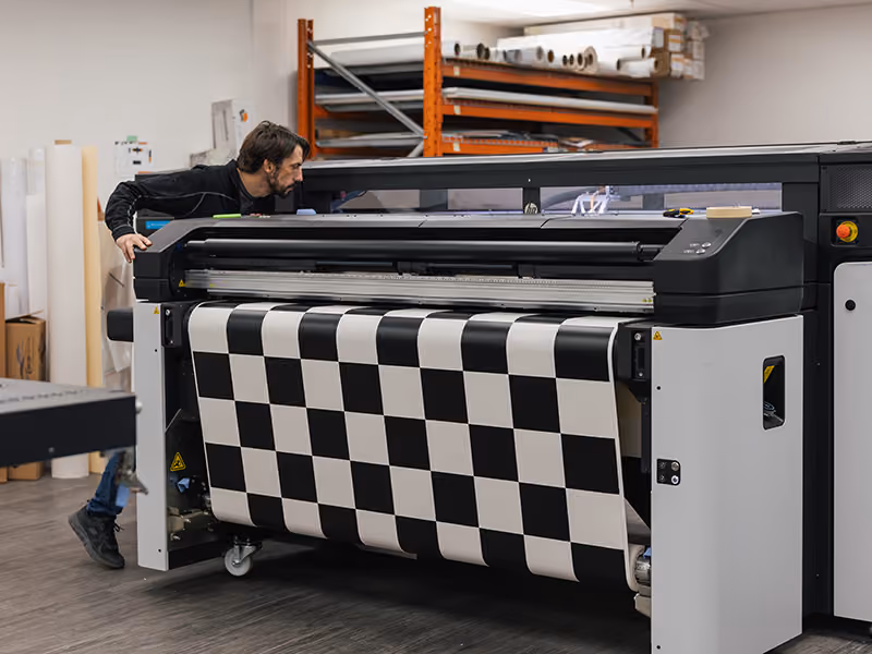 Large-format printer producing checkered graphics for the custom Coca-Cola Ink Studio seacan build.