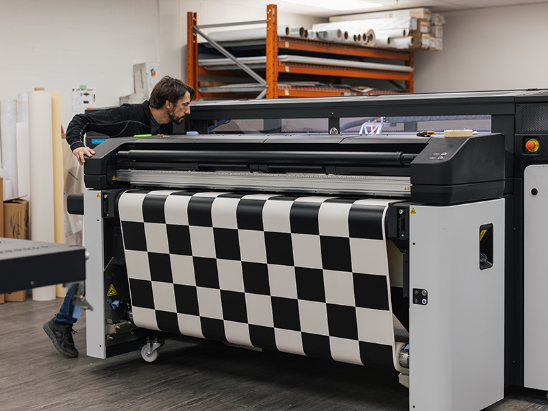 Large-format printer producing checkered graphics for the custom Coca-Cola Ink Studio seacan build.