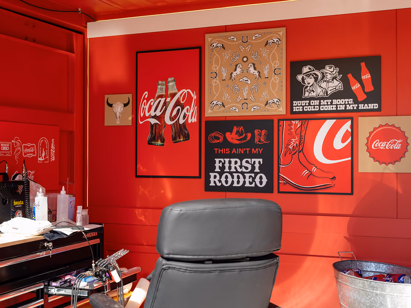 Cowboy-themed Coca-Cola artwork and tattoo chair along the custom-built interior wall of the Ink Studio seacan.
