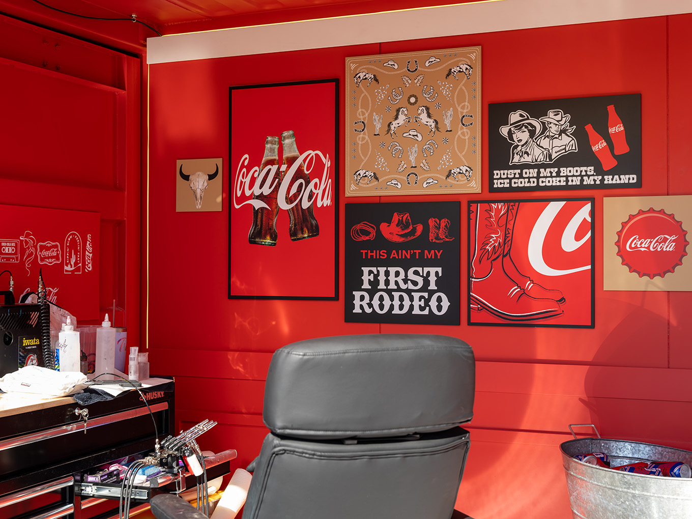 Cowboy-themed Coca-Cola artwork and tattoo chair along the custom-built interior wall of the Ink Studio seacan.