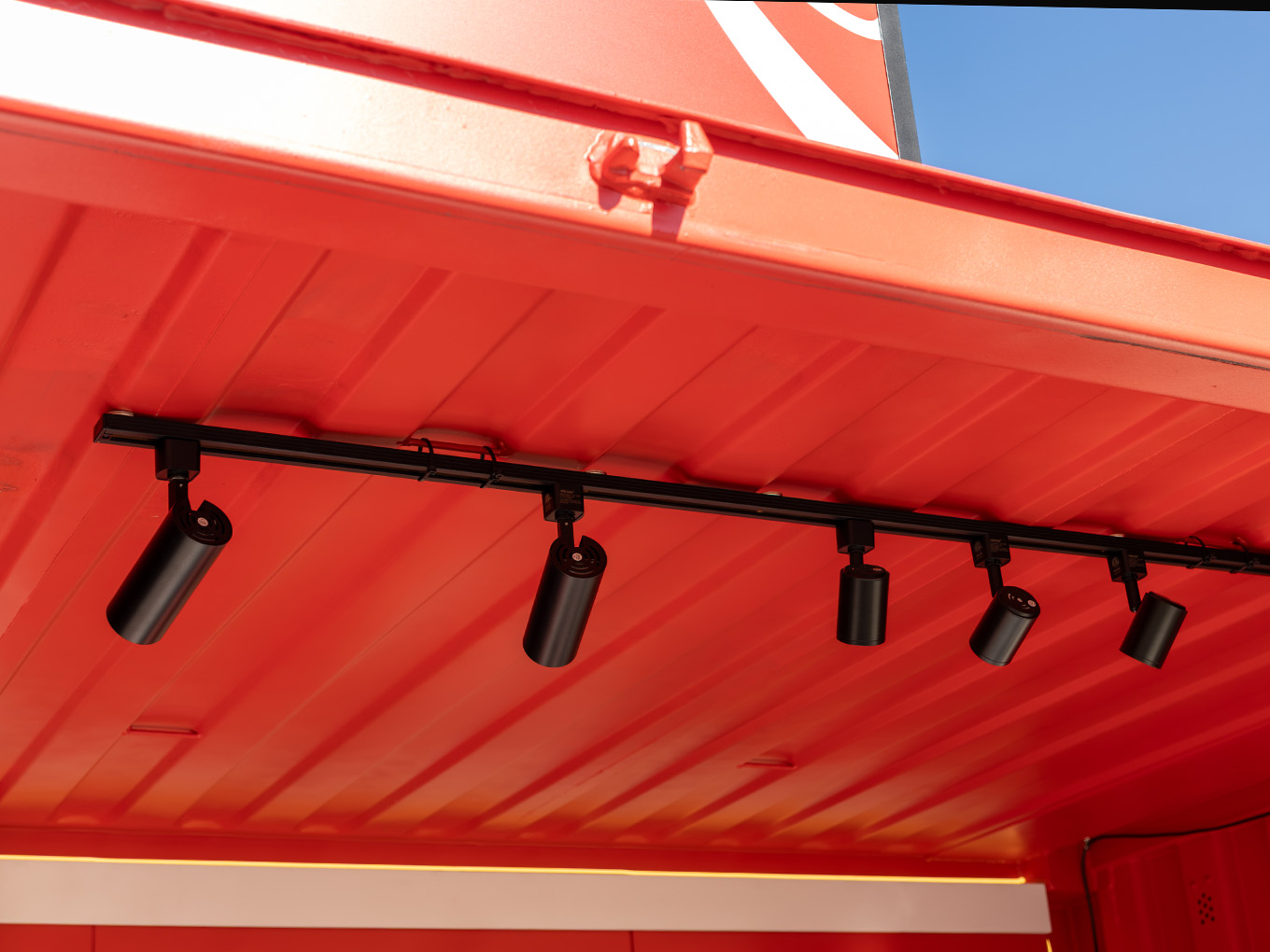 Detail of custom track lighting installed along the interior ceiling of the Coca-Cola Ink Studio seacan.