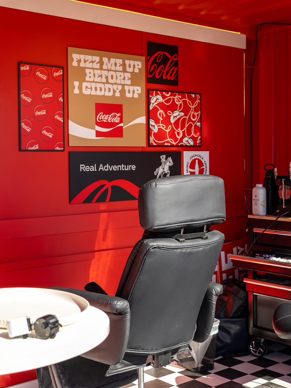 Tattoo chair and custom Coca-Cola cowboy graphics arranged along the seacan's fabricated feature wall.