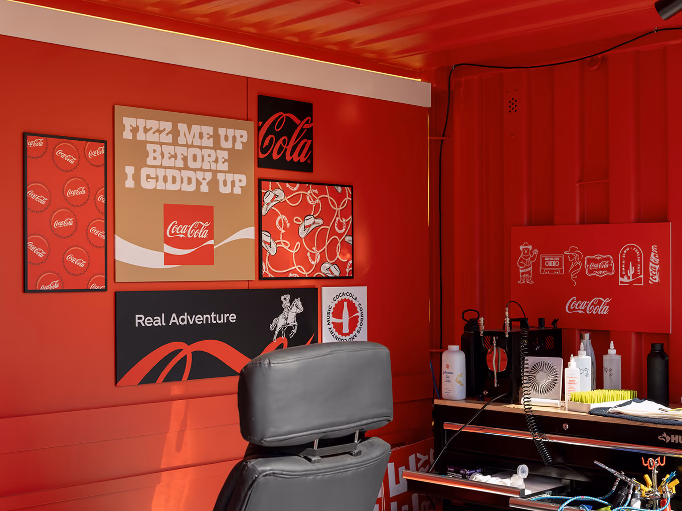 Custom rodeo-themed graphic panels and tattoo workstation inside the Coca-Cola Ink Studio seacan build.