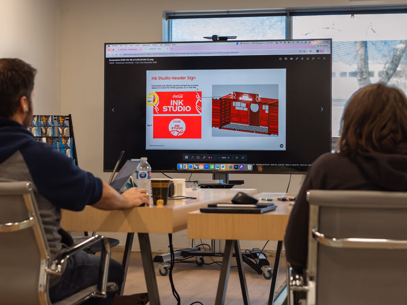Exhibit Studio team reviewing Ink Studio header sign concepts on screen.  15. gallery-15_cokeSeacan_calgaryStampede.jpg Alt text: Exhibit Studio fabricator finishing 3D renderings of custom signage details on the Coca-Cola Ink Studio build. 